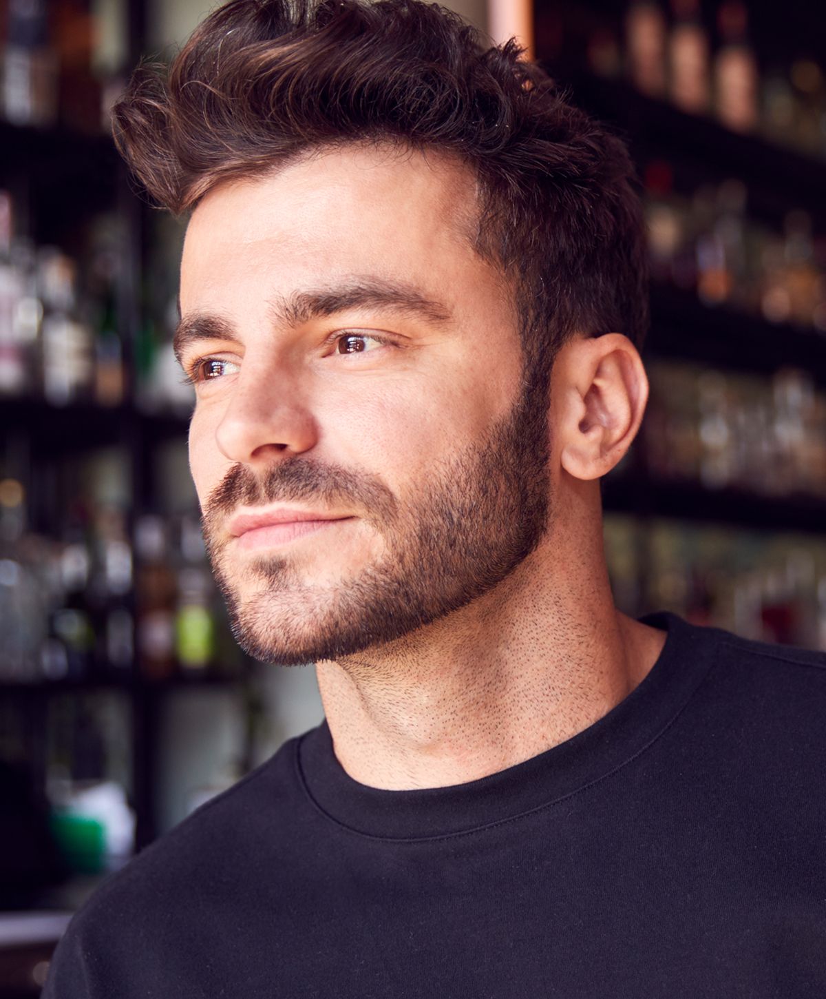 Man with beard and stylish hair, smiling softly.