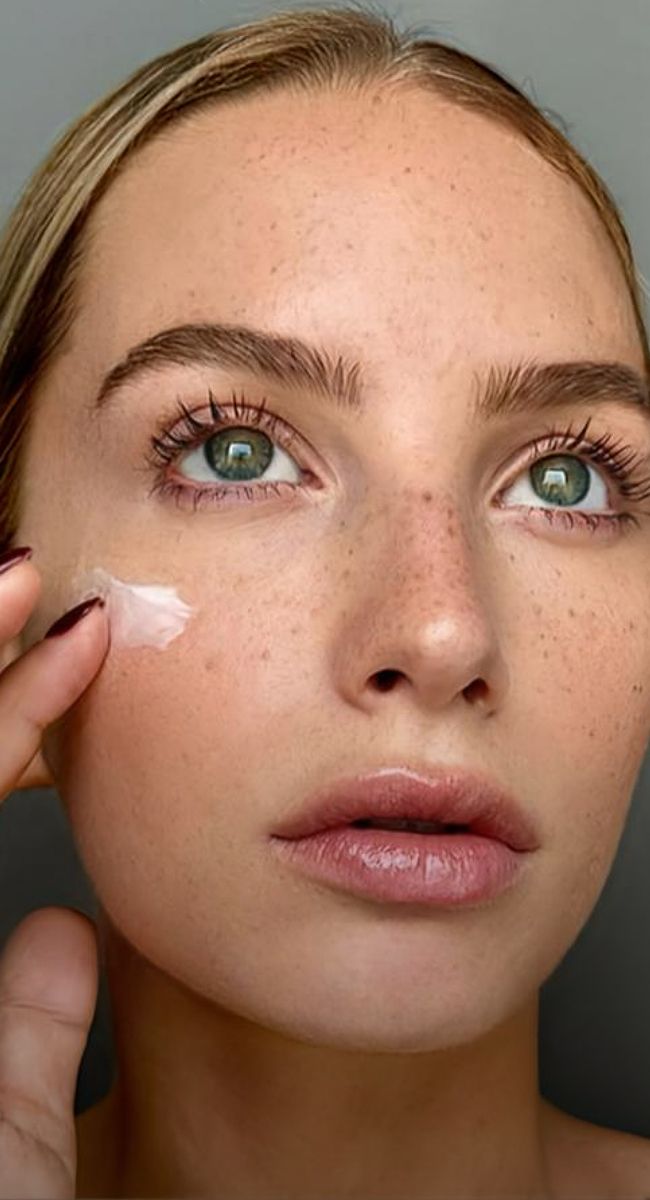 Woman elegantly showcasing jewelry with soft makeup.