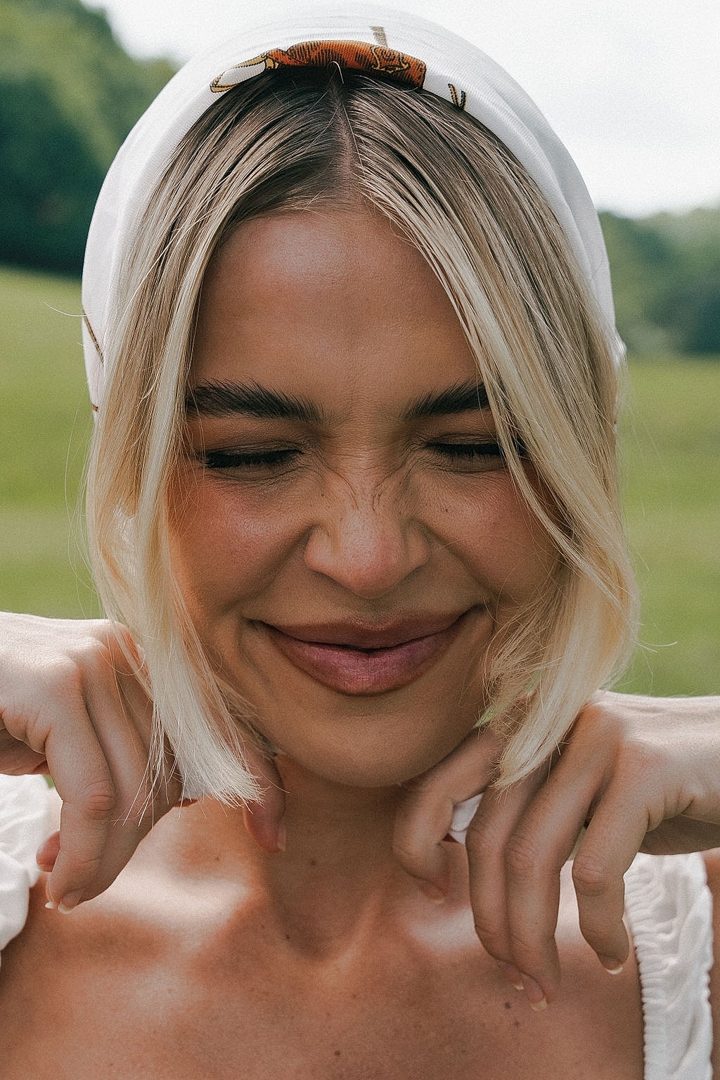 Smiling woman with blonde hair and headscarf.