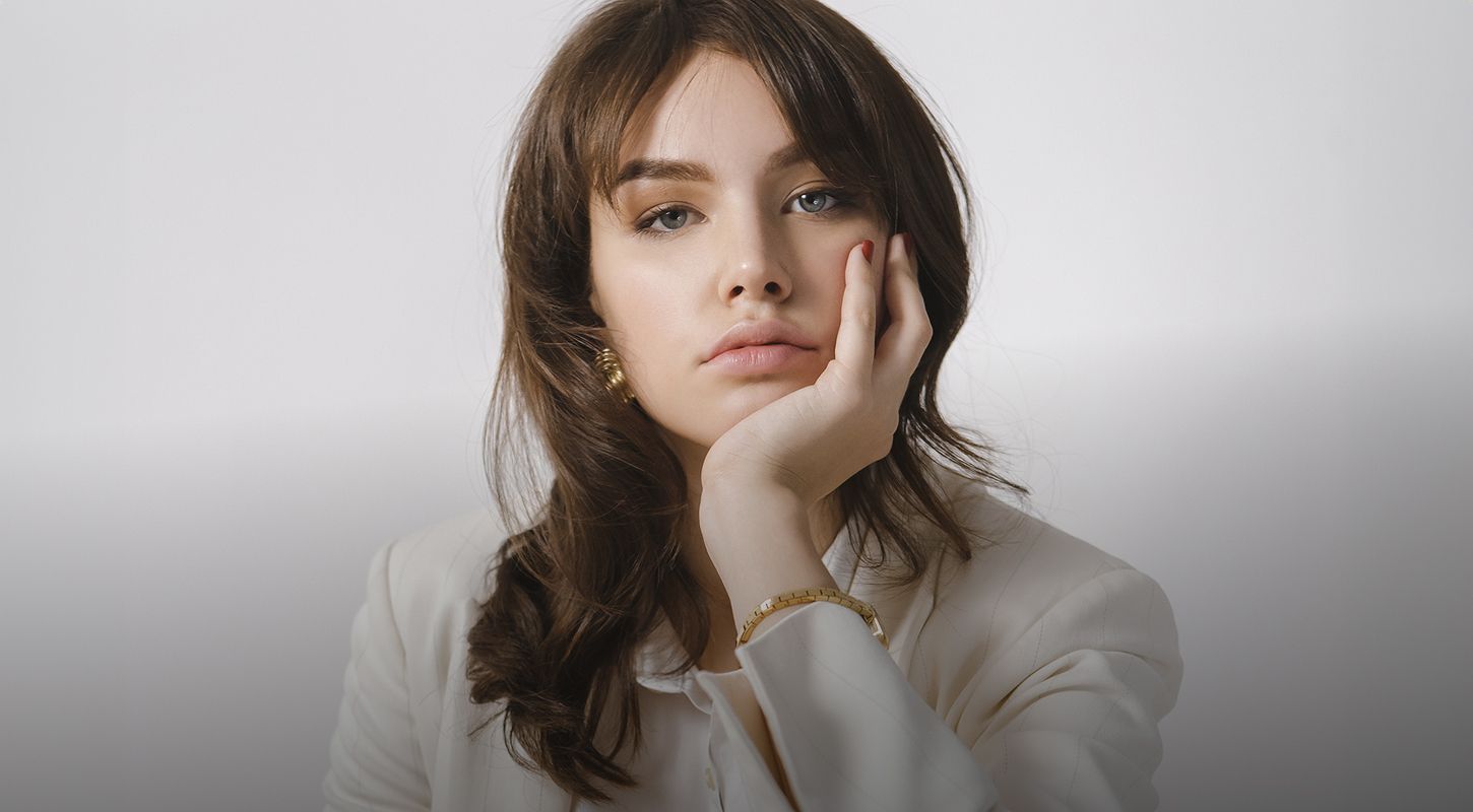 Person with thoughtful expression in white blazer.