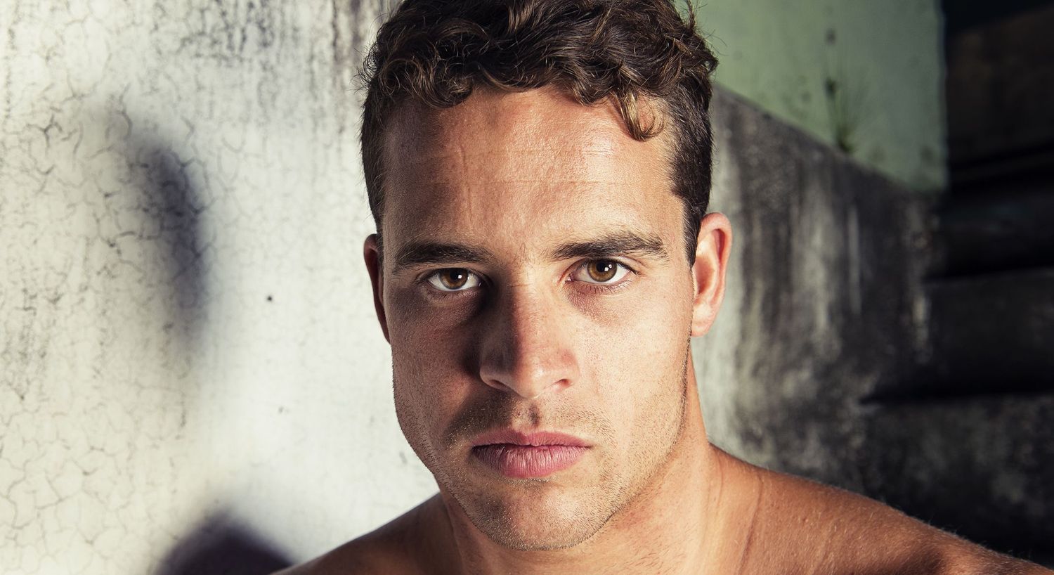 Intense portrait of a man against textured wall.