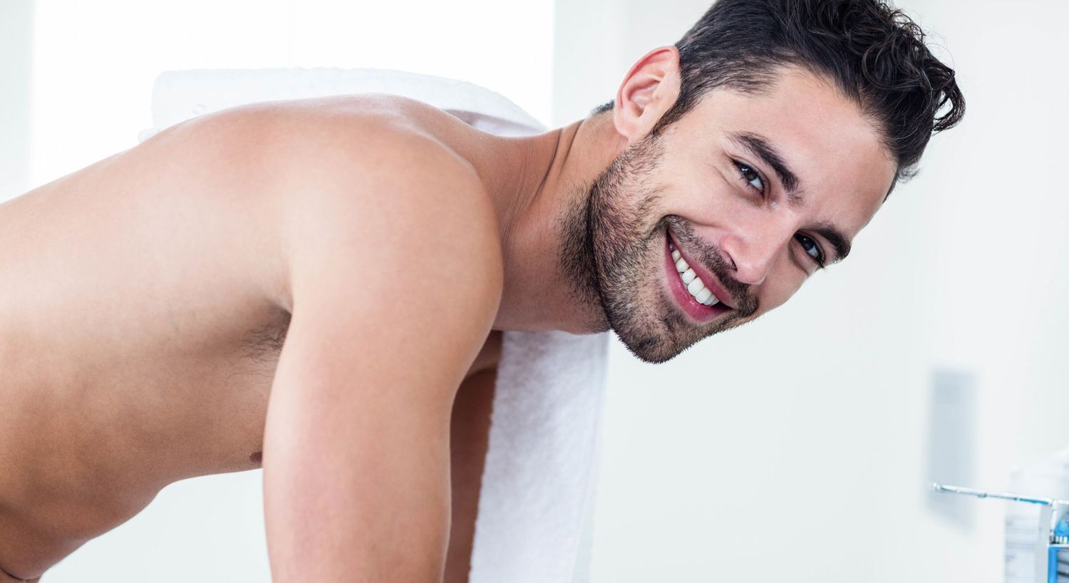 Smiling man with towel in modern bathroom setting.