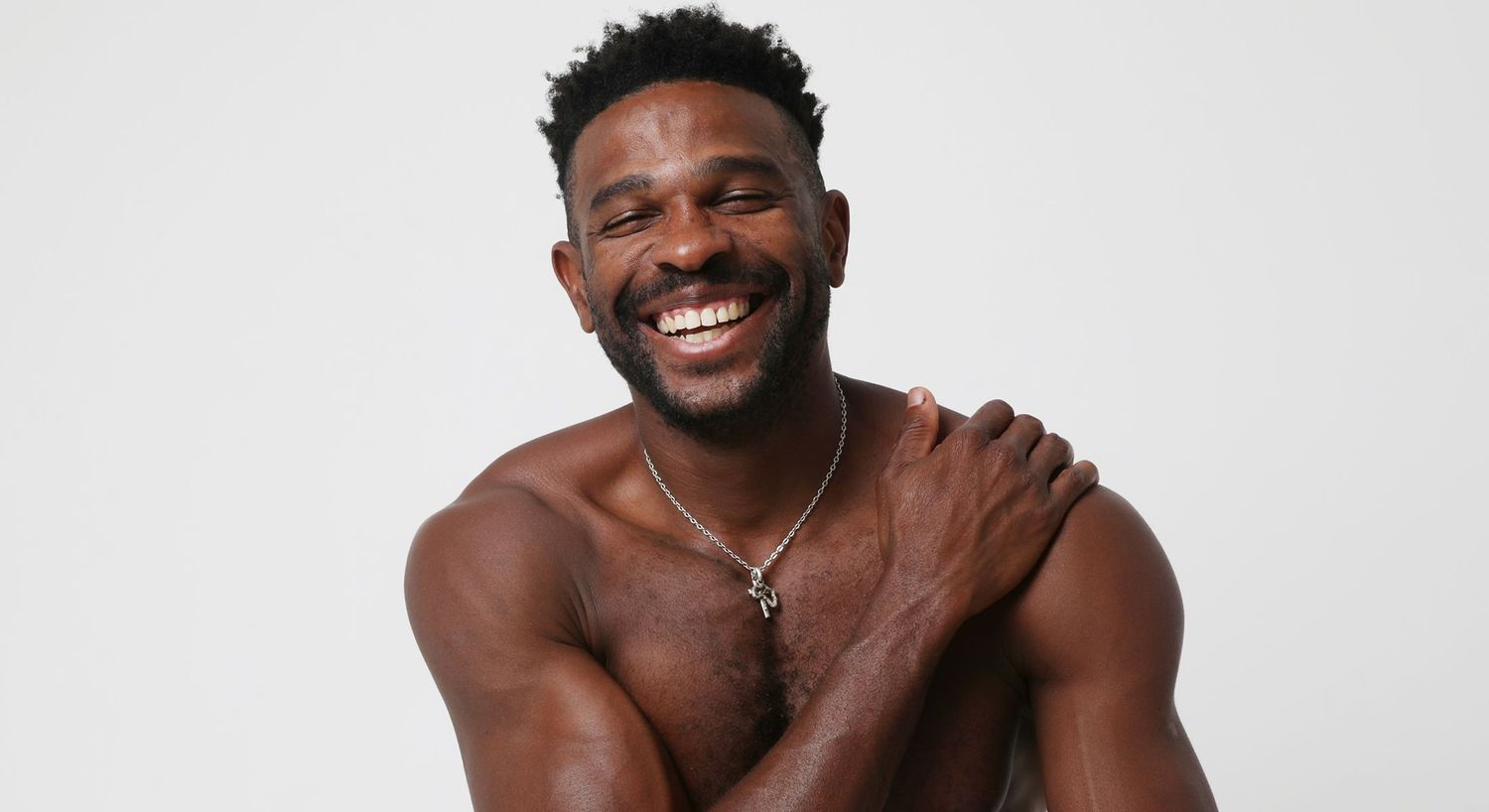 Smiling man with a necklace against white background.