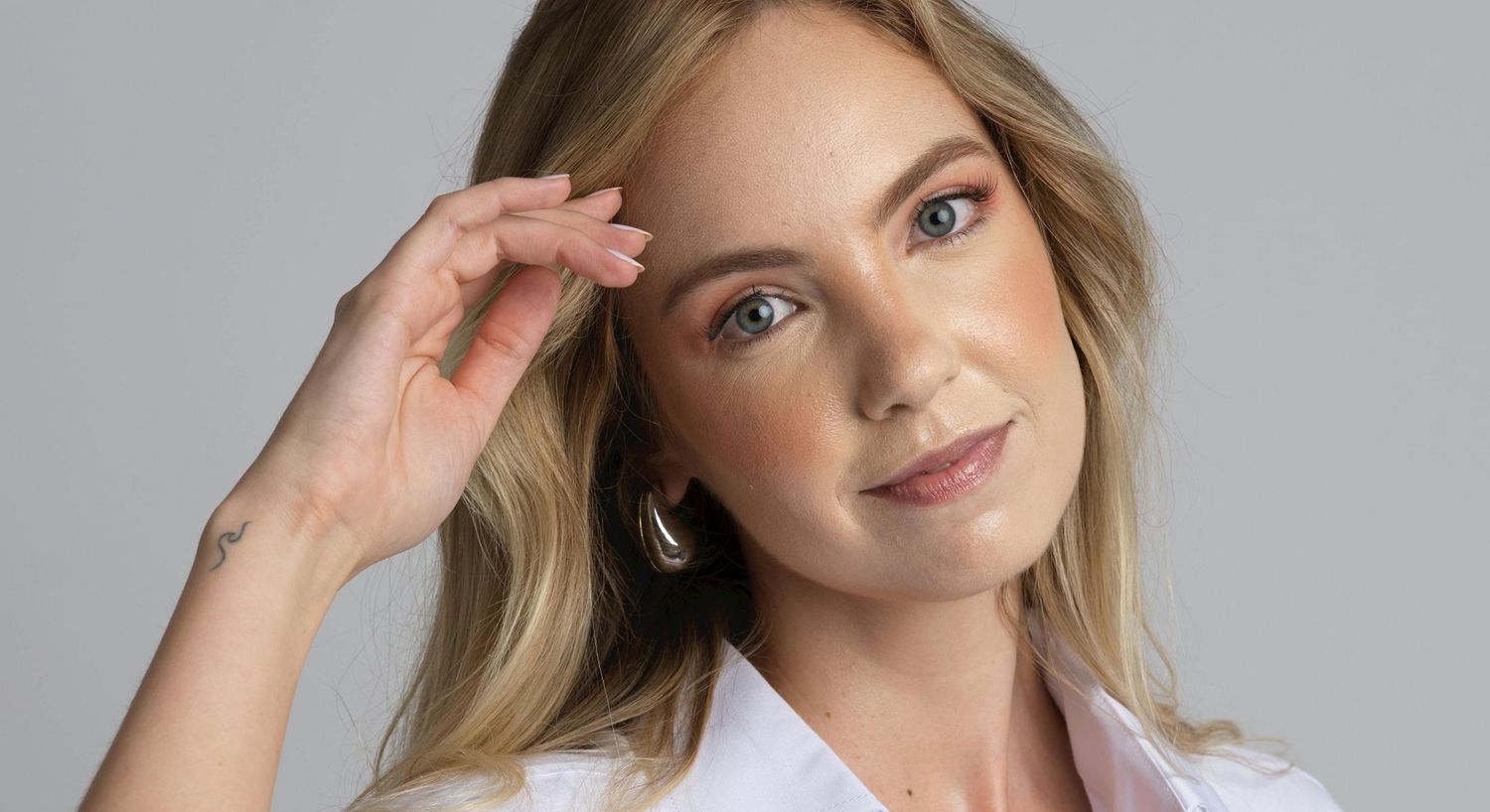 Woman posing with hand in hair, serene expression.