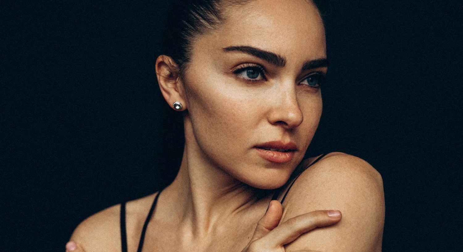 Woman with elegant features against dark background.
